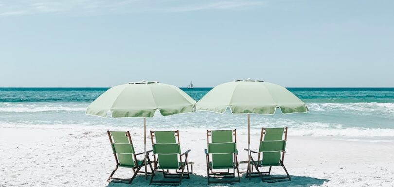 green chairs under umbrellas on shore